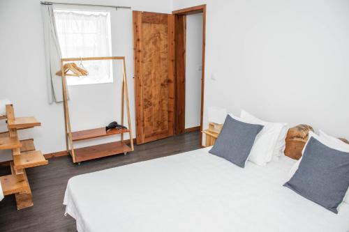 1 dormitorio con 1 cama blanca grande con almohadas azules en Casa Medronho, en São Mateus