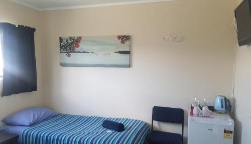 a room with a bed and a picture on the wall at Centabay Lodge and Backpackers in Paihia