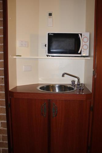 Una encimera de cocina con fregadero y microondas. en Acacia Motor Inn, en Armidale