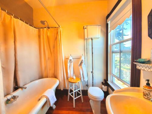 a bathroom with a tub and a toilet and a window at Captain's Inn at Moss Landing in Moss Landing