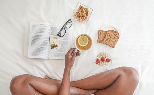 a woman in panties sitting on a bed with a book and food at Wine Stone Inn in Santa Maria