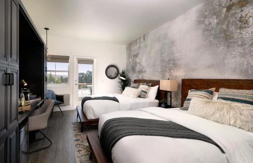 a bedroom with two beds and a desk and a mirror at Wine Stone Inn in Santa Maria