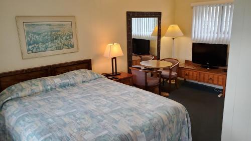 1 dormitorio con 1 cama y 1 mesa con sillas en Wasaga Beach Inn And Cottages en Wasaga Beach