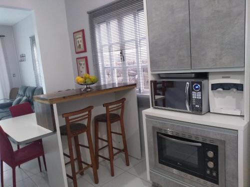 cocina con microondas, mesa y sillas en Casa aconchegante Joaquina, en Florianópolis