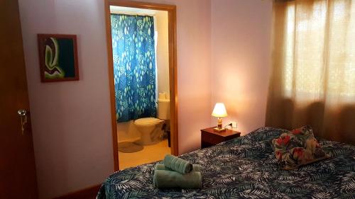 a bedroom with a bed and a bathroom with a toilet at Uka Vaikava in Hanga Roa