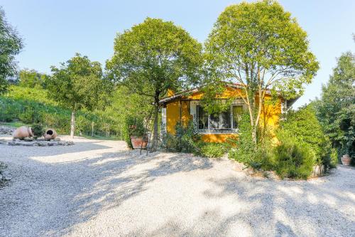 a yellow house on a gravel road with trees at Villa Pongina with private pool in Montevarchi