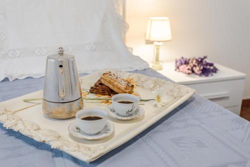 a tray with two cups of coffee and cookies on a bed at Villa Pongina with private pool in Montevarchi