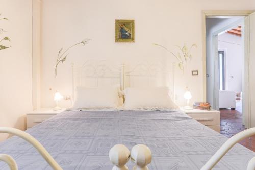 a white bedroom with a large bed with white pillows at Villa Pongina with private pool in Montevarchi