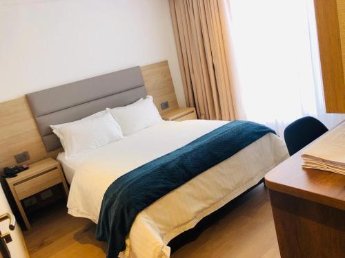 a bedroom with a bed with a blue blanket on it at Turrim Dei Hotel Boutique in Barbosa