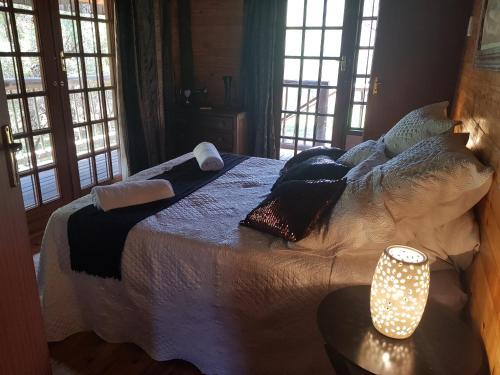 een slaapkamer met een bed en een tafel met een lamp bij Cozy Wood Cabin in Pretoria
