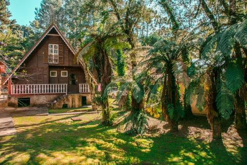 a house with a large tree in front of it at Chalé do Vale Encantado in Campos do Jordão