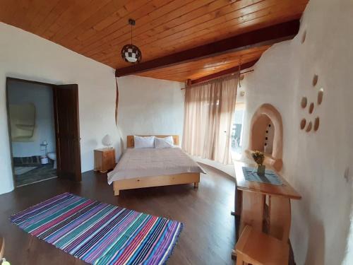 sypialnia z łóżkiem i drewnianym sufitem w obiekcie Cob Village w mieście Berca