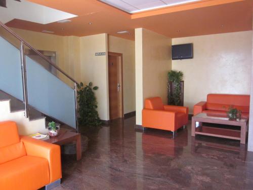 un vestíbulo de oficina con sillas naranjas y una escalera en Hotel Totana Sur en Totana