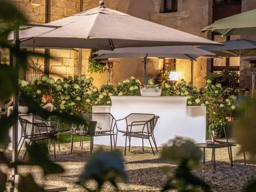 a table and chairs with an umbrella in a garden at Hotel De Bourbon Grand Hotel Mercure Bourges in Bourges