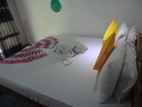 a bed with white sheets and colorful pillows at Lovely lodge & Hostel in Sigiriya