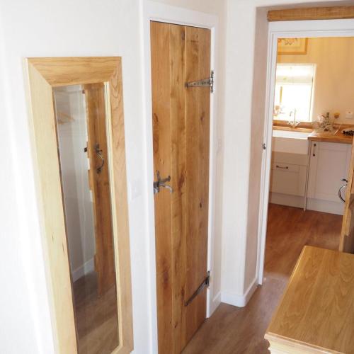 a bathroom with a wooden door in a room at The Tack Room Cottage in Blandford Forum