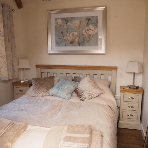 a bedroom with a bed with two night stands and two lamps at The Tack Room Cottage in Blandford Forum