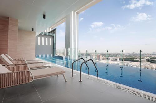 a swimming pool with benches and a large window at Millennium Executive Apartments Mont Rose in Dubai