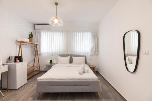 a white bedroom with a bed and a mirror at 36 Geula - By Beach Apartments TLV in Tel Aviv