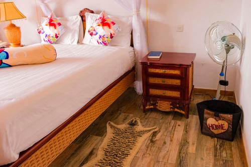 a bedroom with a bed with a fan and a table at Fort Fun City Hotel Fort Portal in Fort Portal