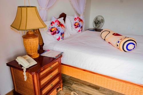 a bedroom with a bed with a lamp and a telephone at Fort Fun City Hotel Fort Portal in Fort Portal