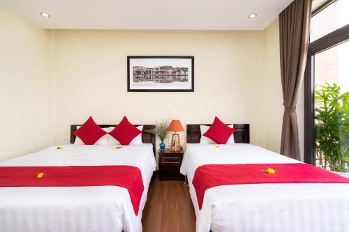 two beds in a room with red and white sheets at Ancient River Villa in Hoi An