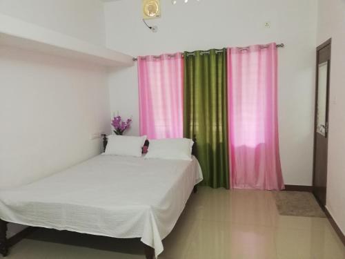 a bedroom with a bed and pink and green curtains at Takashi Homestay North Paravur Near Muziris in North Paravur