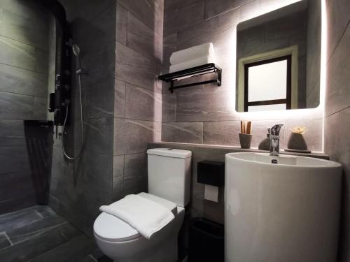 a bathroom with a toilet and a sink and a mirror at Oikos Poshtel in Kota Kinabalu