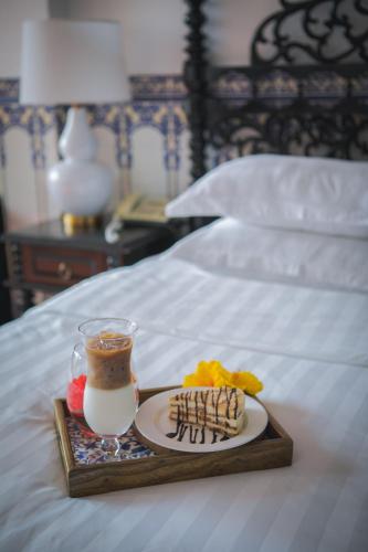 a tray with a plate of food and a drink on a bed at Pousada de Coloane Boutique Hotel in Macau