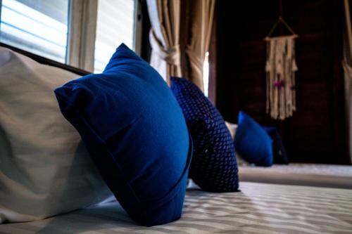 three blue pillows sitting on a bed with a window at Baan Suan Krung Kao in Phra Nakhon Si Ayutthaya