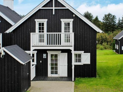 a black barn with white doors and a porch at 8 person holiday home in Gjern in Gjern