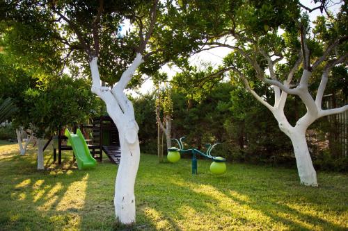 un parque con 2 árboles y un parque infantil en Akroyali Hotel & Villas, en Agios Andreas - Mesenia