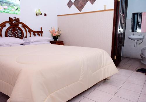 1 dormitorio con cama blanca y aseo en Fortuna Guest House en Yogyakarta