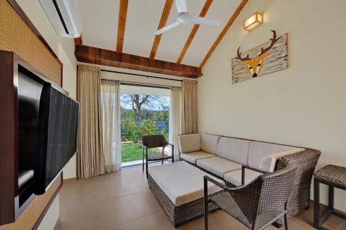 a living room with a couch and a flat screen tv at The Fern Sattva Resort - Polo Forest in Vijayanagar