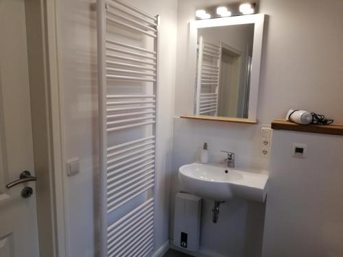 a white bathroom with a sink and a mirror at Fachwerkkate in Vögelsen
