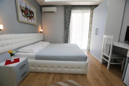 a bedroom with a white bed and a desk and a desk at Hotel Vila Verde City Center in Tirana