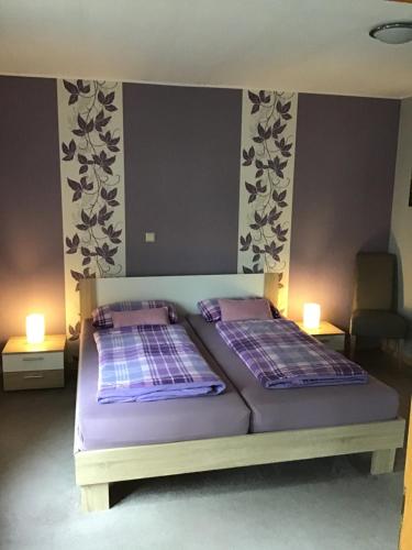 two beds in a bedroom with two lights on the wall at Ferienwohnung am Wiehengebirge in Hüllhorst