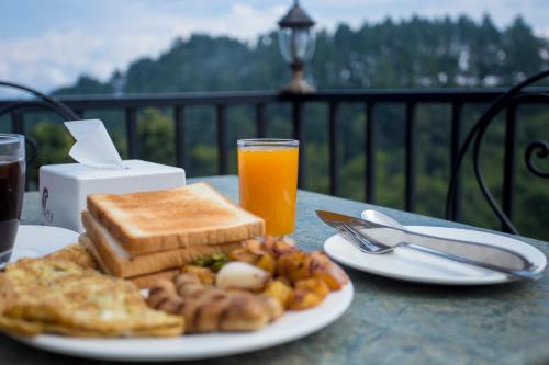 a plate of breakfast food and a glass of orange juice at Depche Village Resort in Bandīpur