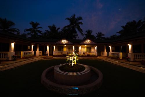 a house with a palm tree in front of it at night at C Roque Beach Resort in Colva