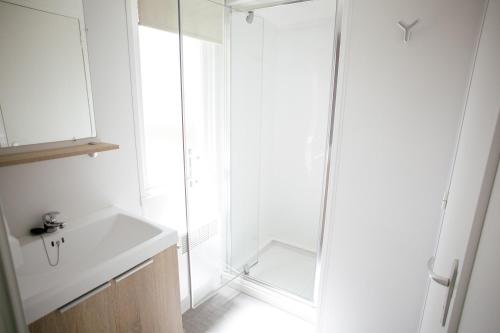 a white bathroom with a sink and a shower at Camping Saint Michel in Courtils