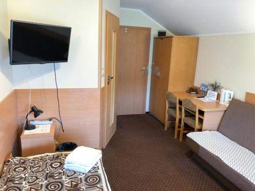 Habitación de hotel con cama y TV en la pared en Motel Orion, en Piła