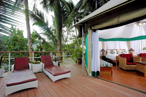 a room with a bed and chairs on a deck at Canvas & Orchids Retreat in Tatai