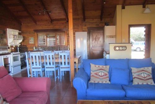 a living room with a blue couch and a kitchen at CHARMING BEACH BUNGALOW in Cape St Francis