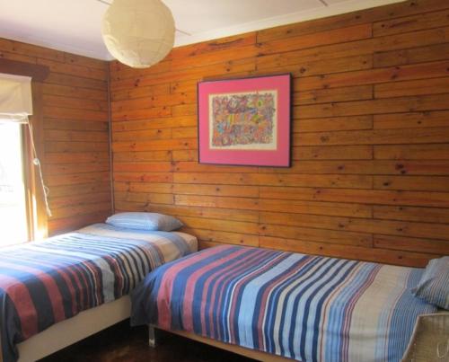 two beds in a room with wooden walls at CHARMING BEACH BUNGALOW in Cape St Francis