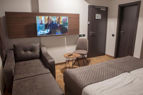 プリシュティナにあるQama Hotelのベッド、ソファ、テレビが備わるホテルルームです。