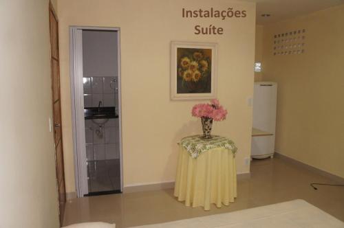 um quarto com um vaso de flores sobre uma mesa em Apto Praia de Setiba em Una