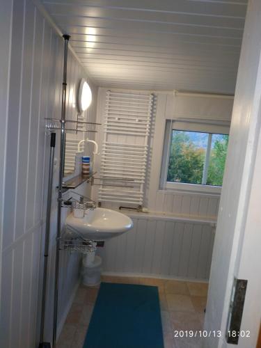 a white bathroom with a sink and a window at Pension Panorama in Tanvald