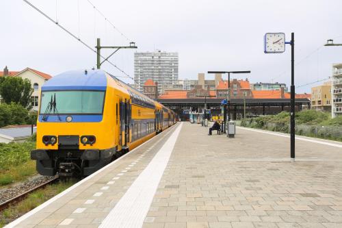 a yellow and blue train pulling into a train station at Hotel La Rosa Amsterdam Beach in Zandvoort