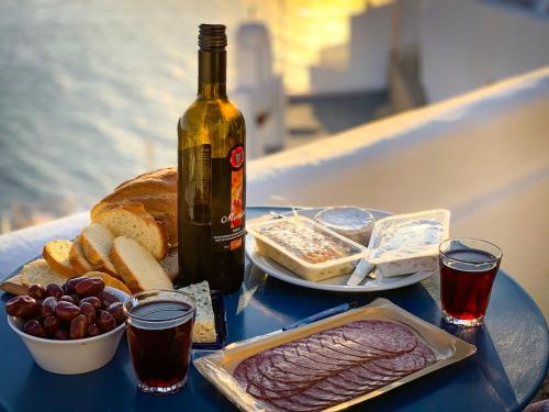 a table with a bottle of wine and a plate of food at Fotinos Houses in Oia
