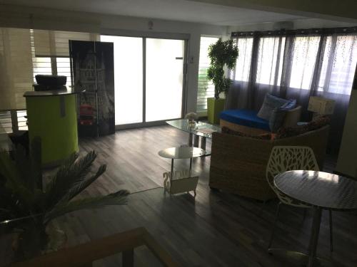 ein Wohnzimmer mit einem Sofa, Tischen und Fenstern in der Unterkunft SERENADE Lodging Rooms in Panama-Stadt